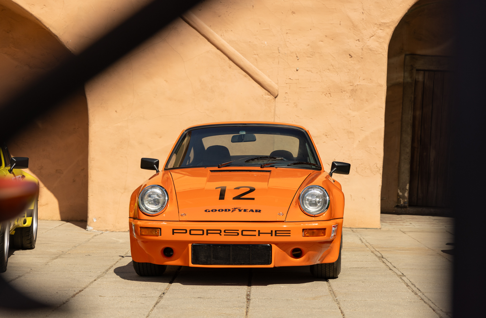 orange Porsche photographed sitting on a scene set
