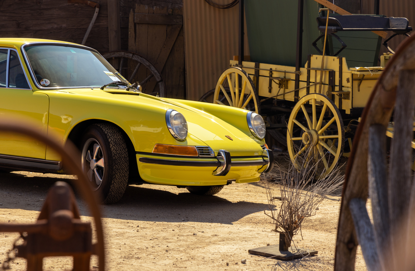 yellow Porsche in middle of dirt parking spot