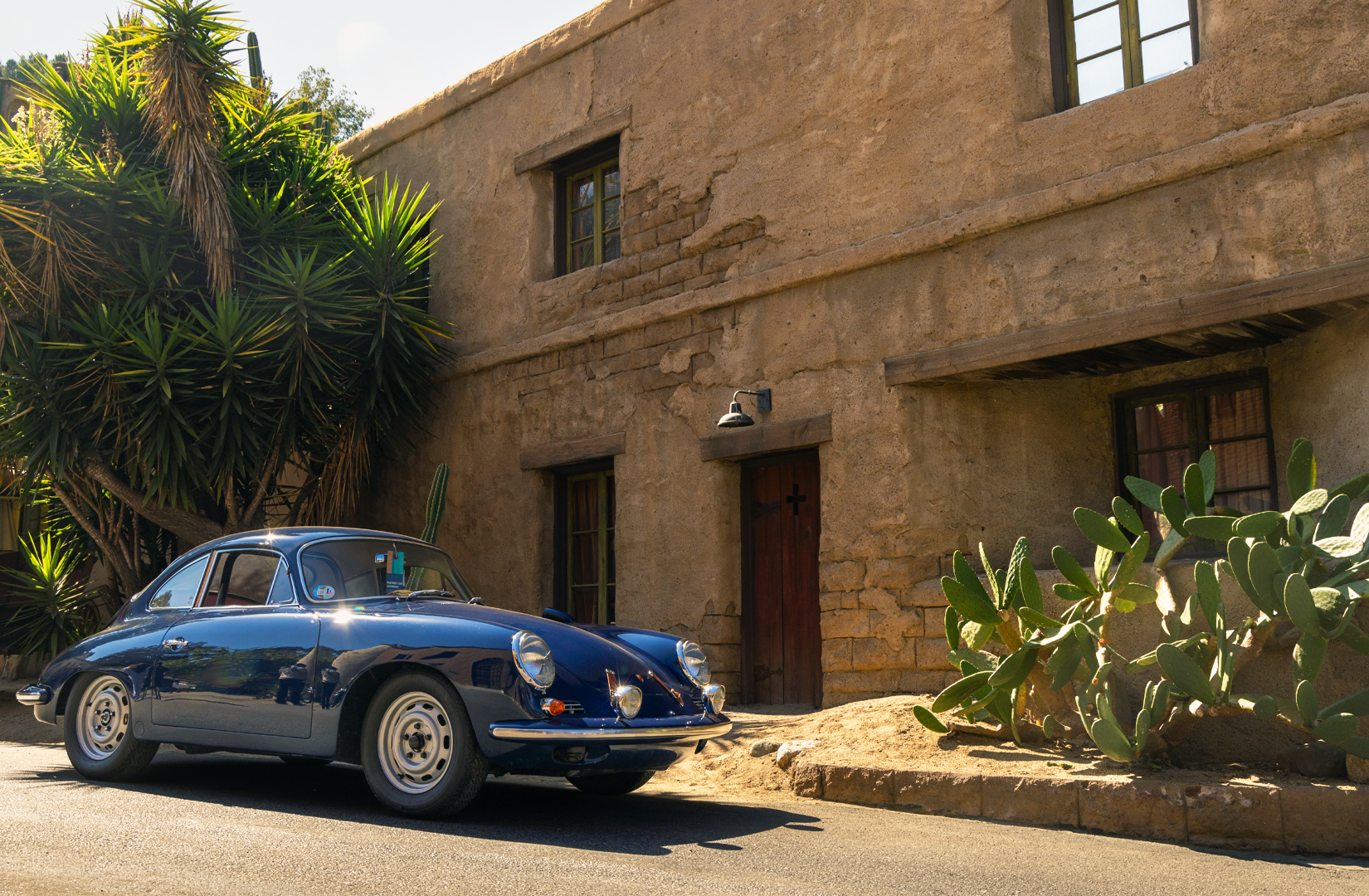 Blue Porsche sitting in front of brown building